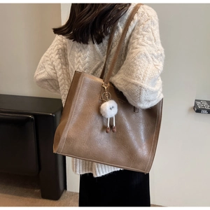 Gros plan du sac fourre-tout marron texturé avec coutures blanches et charm