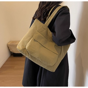 Detail of mustard yellow nylon tote bag with front flap pocket and wide shoulder strap