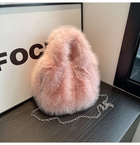 Détail d'un sac à main en peluche rose avec chaîne en métal argenté sur bois foncé