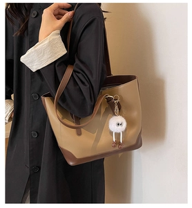Detail of khaki and brown contrast stitching tote bag with plush monster charm