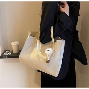 Détail du grand sac cabas crème avec texture cuir et pendentif peluche doux