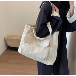 Side view of large nylon tote bag with front flap pocket on model in modern interior