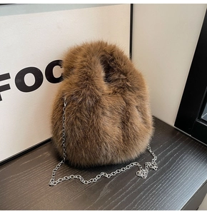 Gros plan sur la texture en fausse fourrure marron et la chaîne en métal de ce sac