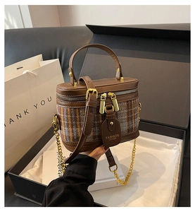 Detail of tweed bucket bag with gold zippers, leather handle and chain strap