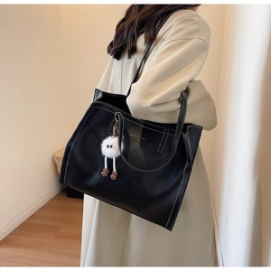 Détail du grand sac cabas noir en cuir avec surpiqûres et pendentif en peluche
