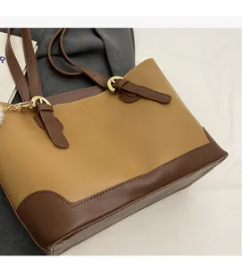 Detail of adjustable dark brown leather straps and golden metal buckles on a khaki tote bag