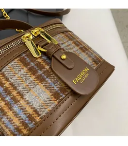 Detail of brown plaid tweed shoulder bag showing gold chain strap and leather trim
