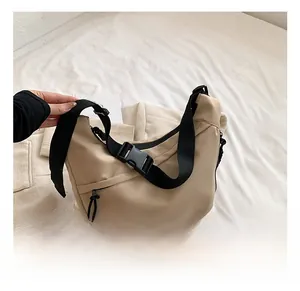 Detail of beige crescent nylon crossbody bag with black adjustable strap and buckle