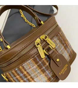 Macro detail of textured tweed and leather bag with smooth double gold zippers