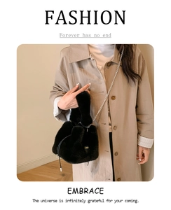 Detail of black faux fur bucket bag with metal chain strap worn over a khaki trench coat