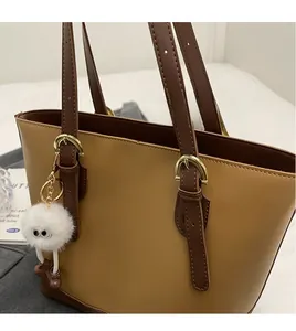 Detail of contrast-color tote bag with adjustable shoulder strap and plush charm