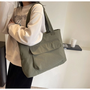 Detailed close-up of olive green nylon tote bag featuring a front flap pocket and water-resistant texture