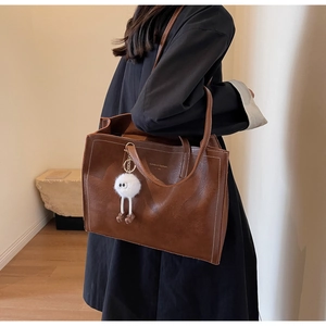 Détail du grand sac cabas en cuir marron avec surpiqûres blanches et charme peluche