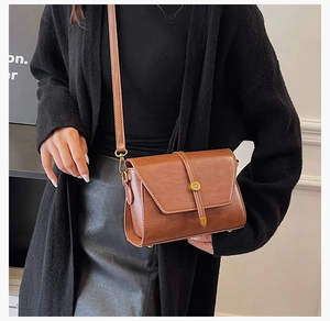 Détail du sac bandoulière en similicuir marron avec boucle dorée ronde et sangle décorative
