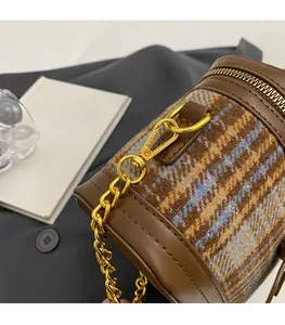 Close-up of golden metal chain and plaid fabric texture on the cylinder bucket bag
