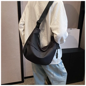 Detail of a large black crescent nylon crossbody bag with woven zipper puller