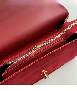 Detail shot of the red leather handbag featuring a gold zipper and internal compartment