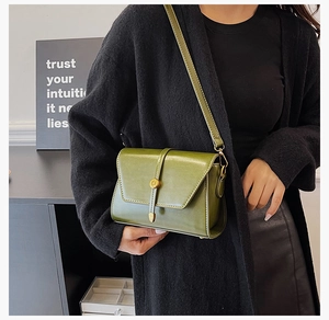 Détail du sac bandoulière vintage en similicuir vert avec boucle ronde sur le mannequin