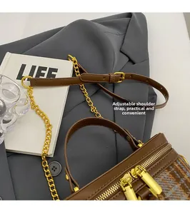 Detail view of brown leather bucket bag with houndstooth stitching and gold chain
