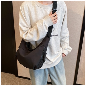 Detail of black nylon crescent hobo bag featuring wide strap and chunky metal zipper