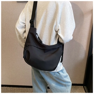 Rear view of a black nylon crossbody crescent bag with a woven zipper pull and wide strap