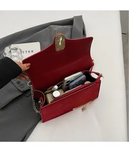 Detail view of red shoulder bag interior showing capacity for phone and cosmetics