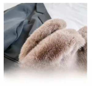 Detail of light brown faux rabbit fur handbag showing dual handles and leather logo tag