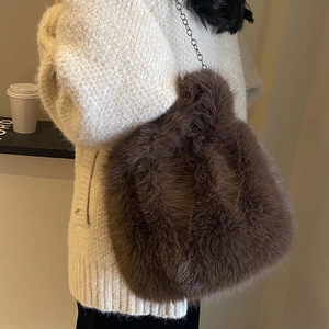 Sac à bandoulière en peluche marron foncé avec chaîne en métal portée par un mannequin