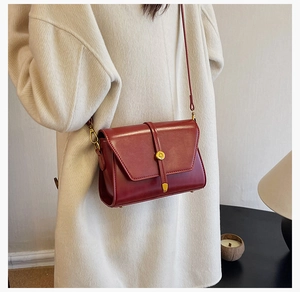 Détail du sac à bandoulière rétro rouge vin avec boucle dorée et texture en PU