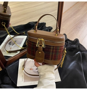 Detail of vintage plaid vanity bag with golden chain strap on a black silk backdrop
