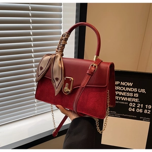 Detail of red PU leather handbag featuring a golden lock and elegant heart silk scarf wrap