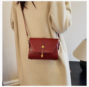Gros plan d'un sac bandoulière bordeaux en cuir PU avec boucle dorée élégante