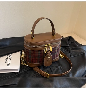 Close-up of retro plaid bucket bag with brown leather flap and gold chain strap