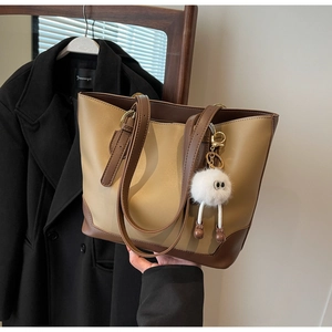 Detail of a large capacity two-tone tote bag with a white plush keychain accessory