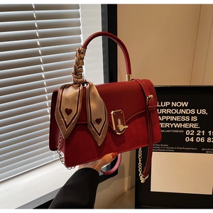 Detail of burgundy PU leather handbag with gold chain, metal lock and heart print scarf