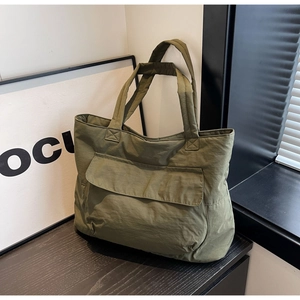 Olive green nylon tote bag featuring a front flap pocket and a minimalist design
