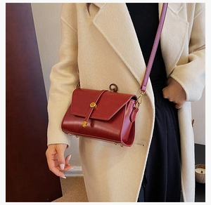 Détail d'un petit sac bandoulière bordeaux en similicuir avec boucle dorée élégante