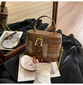 Detail of a brown tweed crossbody bag with golden chain and refined leather finish