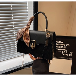 Detail of black faux leather handbag with gold twist lock and heart print scarf handle