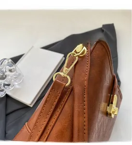 Détail d'un sac à main en cuir marron vintage montrant des ferrures dorées de luxe