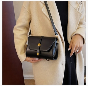 Détail du sac bandoulière en PU noir avec fermoir doré et texture de sangle verticale
