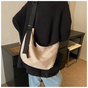 Detail of beige nylon crescent bag featuring wide black strap and woven zipper pulls