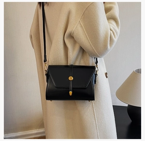 Détail de la bandoulière noire en cuir avec boucle dorée portée par un mannequin