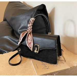 Detail of black leather and suede bag with gold clasp and silk scarf handle decoration