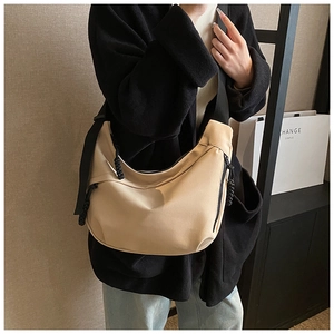 Detail of beige nylon crescent bag with woven zipper pull and black crossbody strap