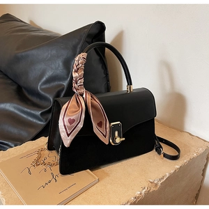 Detail of minimalist PU leather crossbody bag with golden clasp and silk scarf handle