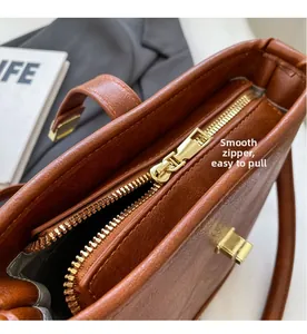 Détail de la fermeture éclair dorée et de la texture cuir de ce sac seau marron