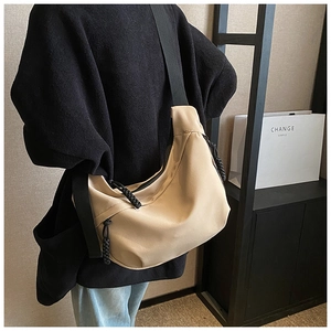 Macro detail of the beige crescent nylon bag with a black shoulder strap and woven zipper
