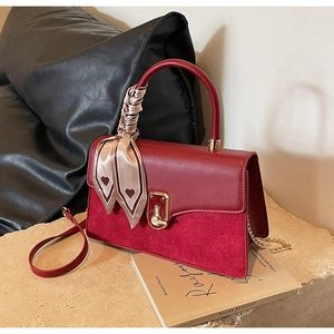 Detail of burgundy PU leather crossbody bag with gold lock and silk scarf on handle