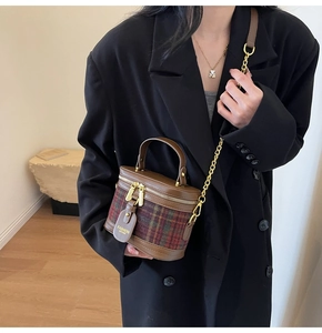 Crossbody view of mini plaid bucket bag with gold chain strap and brown leather trim